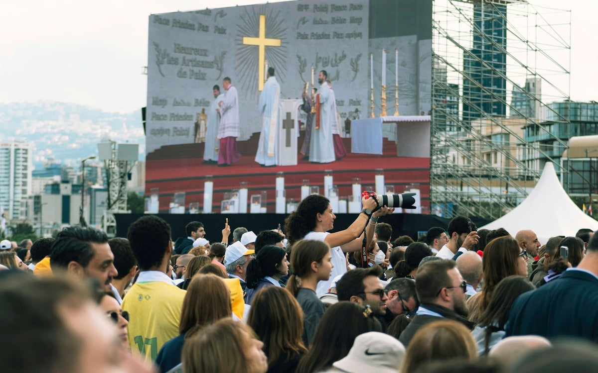 Crowd watches religious ceremony on large outdoor screen